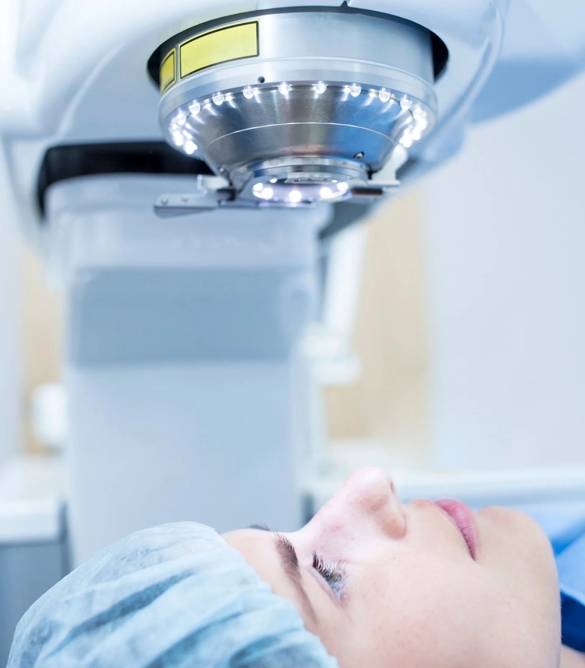 female patient lying down looking up into lasik machine about to undergo procedure