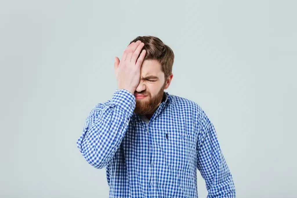 exhausted bearded young man rubbing his eye over white background SBI 302841562 1920w