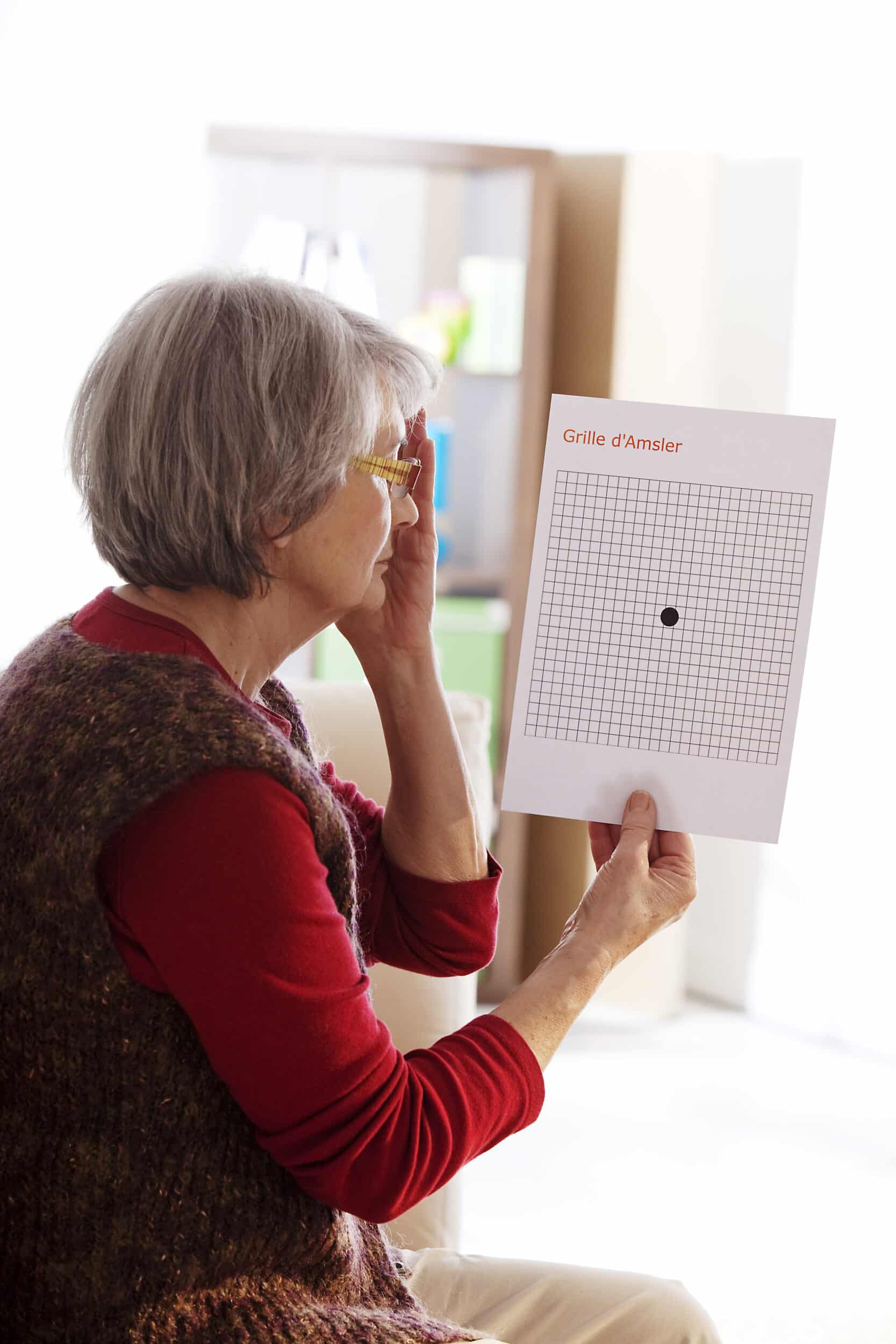 A woman covers one eye and looks at a grid for macular degeneration screening