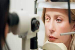 40 year old woman peers into a bright light as her doctor examines her eyes