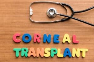 The words "corneal transplant" spelled out in brightly colored blocks, with a stethoscope nearby